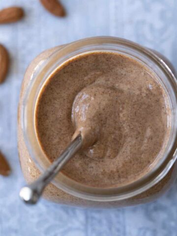 Homemade almond butter in jar with spoon.
