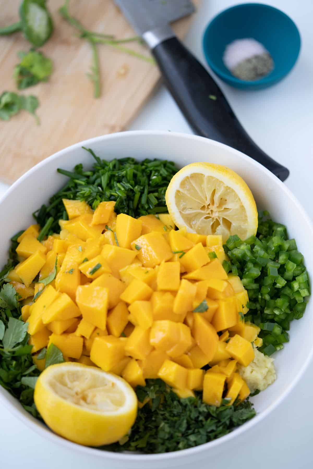 Mango mint salsa chopped up ingredients in a bowl with lemon halves