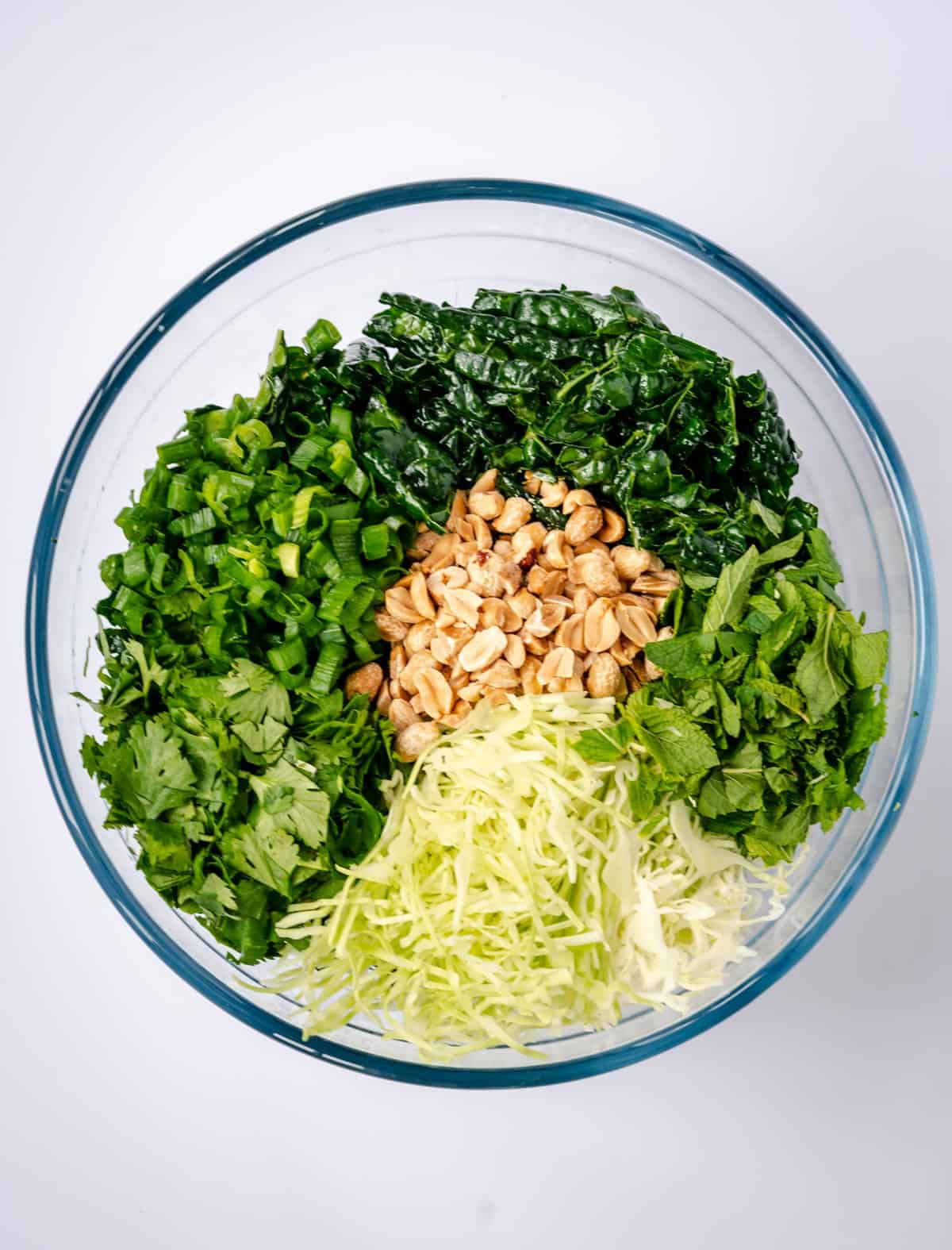 Kale salad ingredients in bowl on top of massaged kale