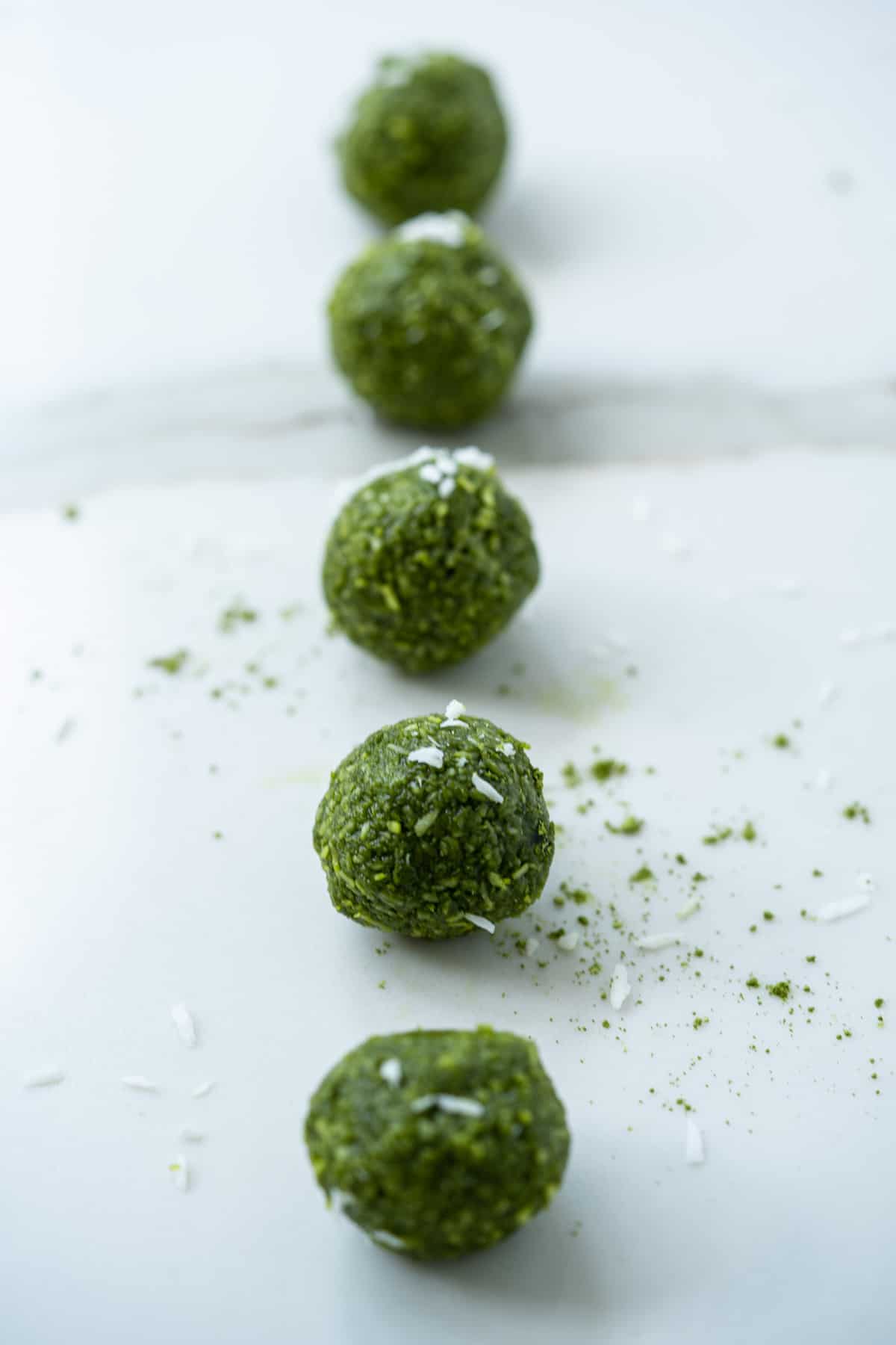 Matcha green tea energy bites lined up in a vertical row