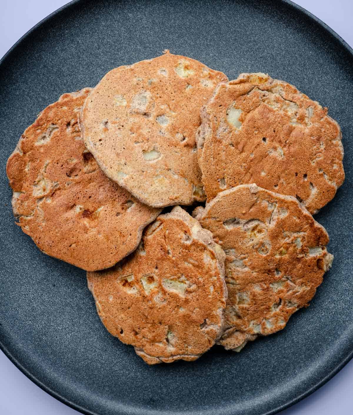 Apple buckwheat pancakes laid flat on a dark grey plate