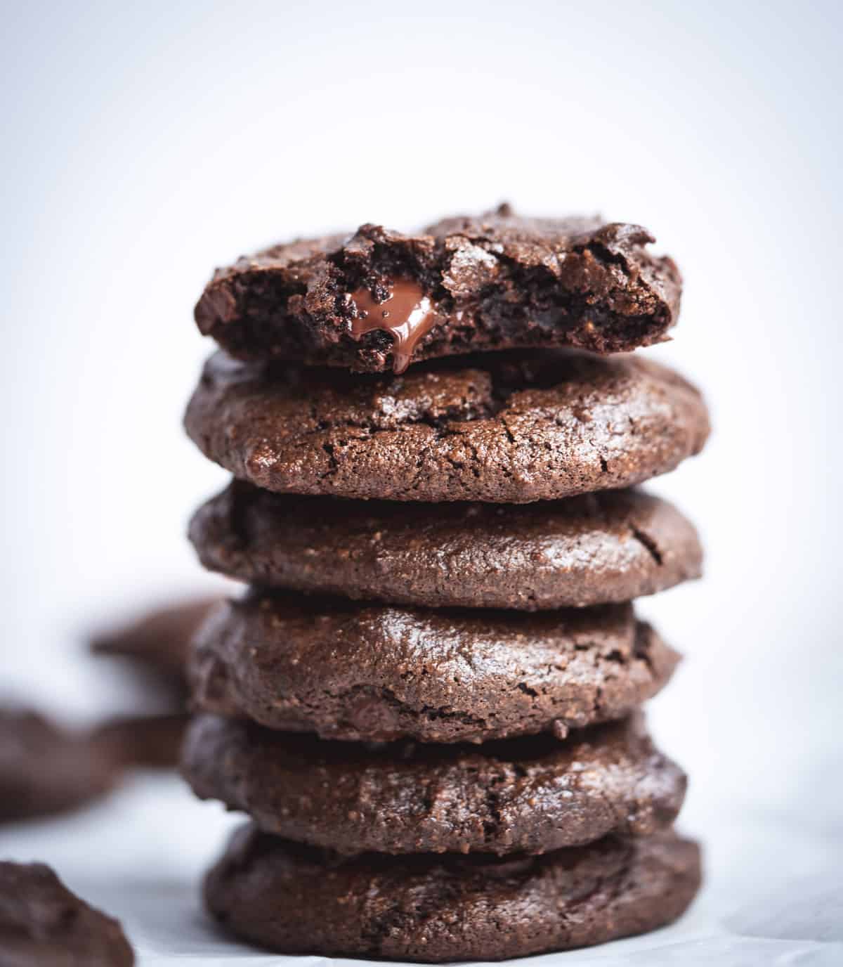 Chocolate fudge tahini cookies stacked with a bite out of one