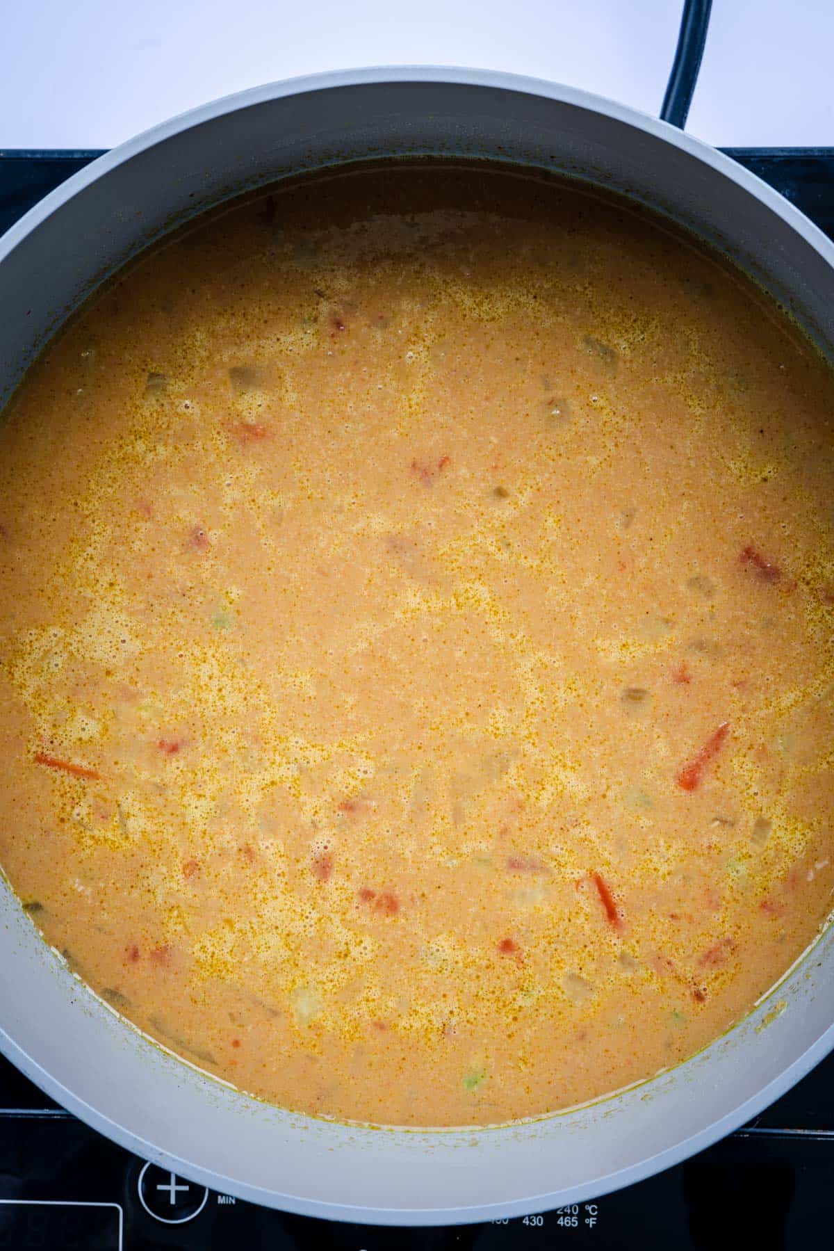 Spicy red lentil soup simmering in pot with all ingredients added