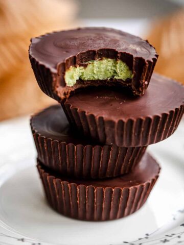 four matcha dark chocolate mint cups stacked with a bite out of the top cup