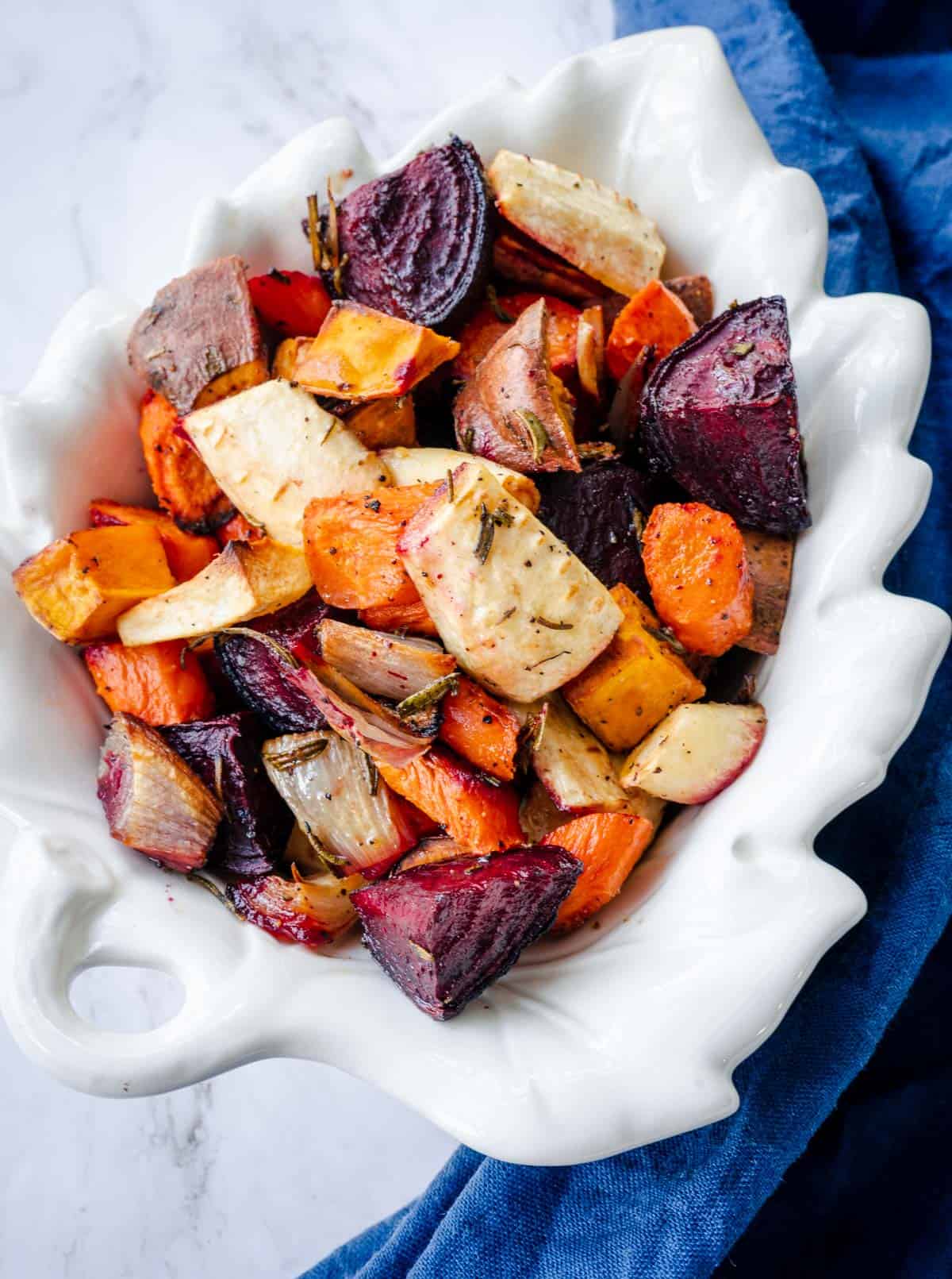 roasted carrots, parsnips, shallots, sweet potato with rosemary in a white dish