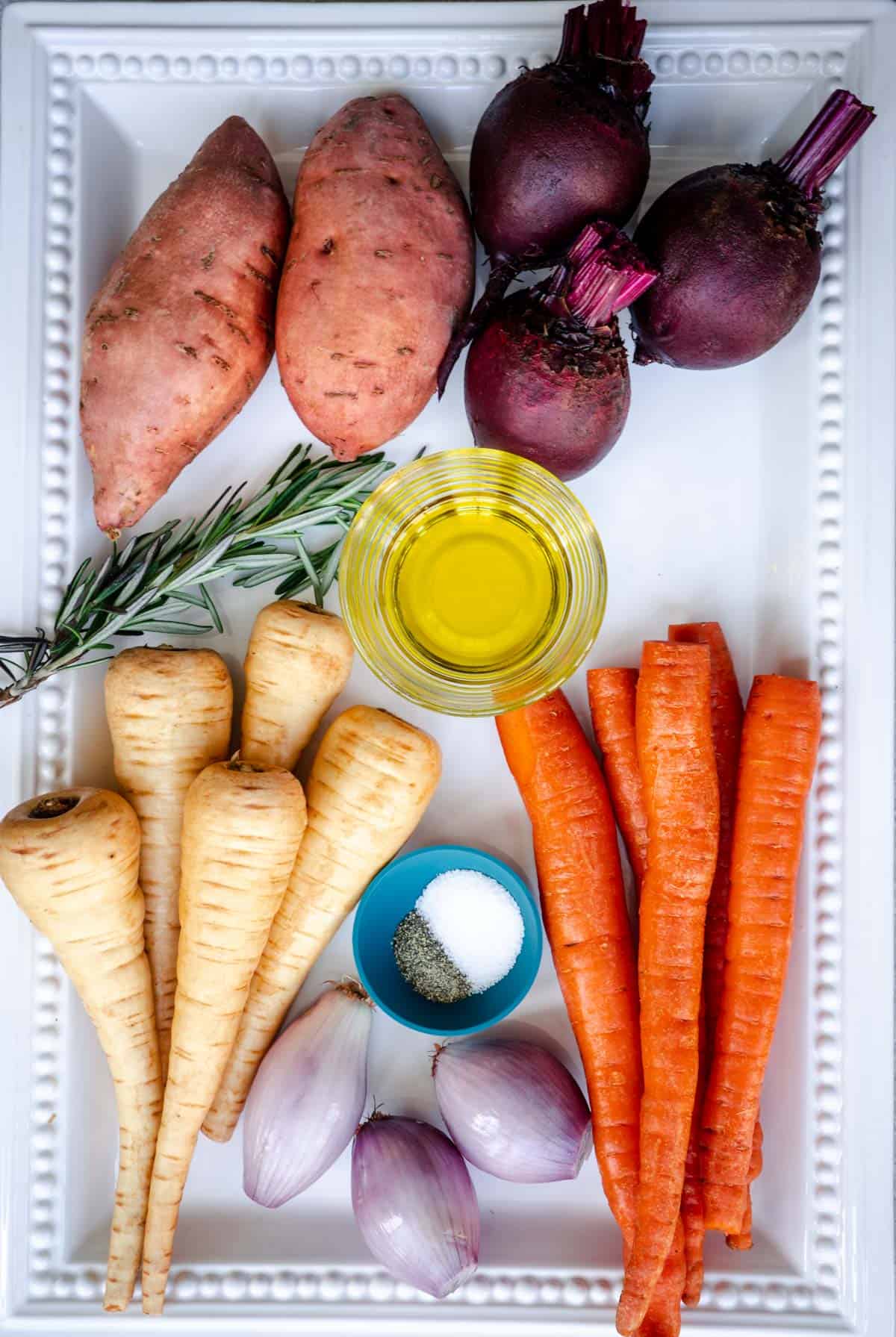 ingredients to make roasted root vegetables, sweet potatoes, beetroots, carrots, parsnips, olive oil, rosemary, shallots, salt and pepper