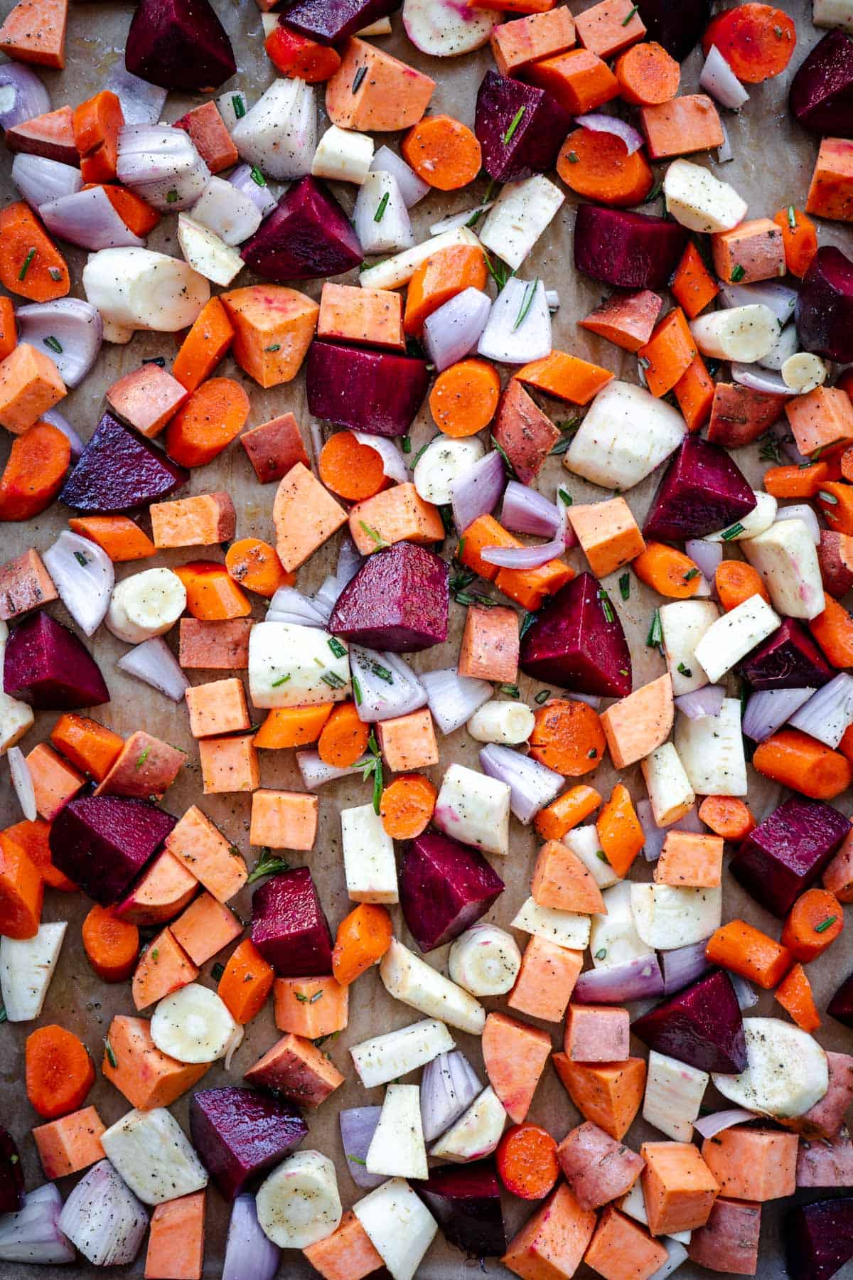 carrots, beets, parnips, sweet potatoes, shallots on a baking tray ready to be tossed in olive oil and roasted