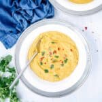 Creamy yellow split pea soup with turmeric in a bowl with spoon and a blue cloth