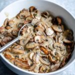 creamy mushroom sauce with coconut milk in white bowl with spoon.
