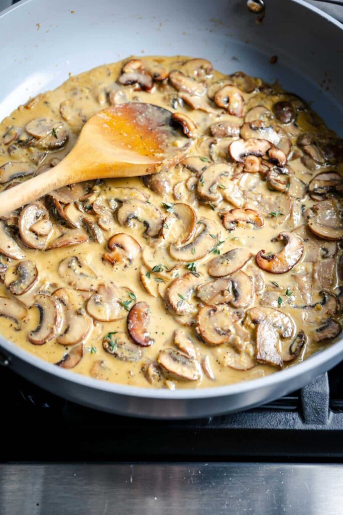 finished creamy mushroom sauce in pan with wooden spoon