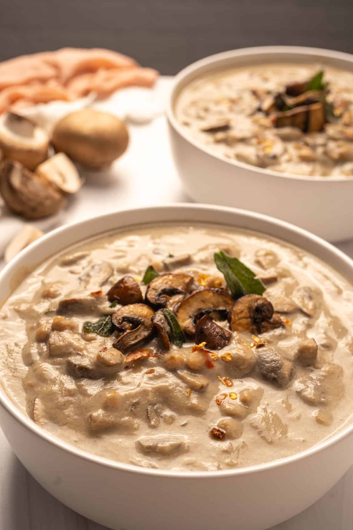 white bean and mushroom soup in a bowl topped with crispy mushrooms, fried sage and crushed red peppers
