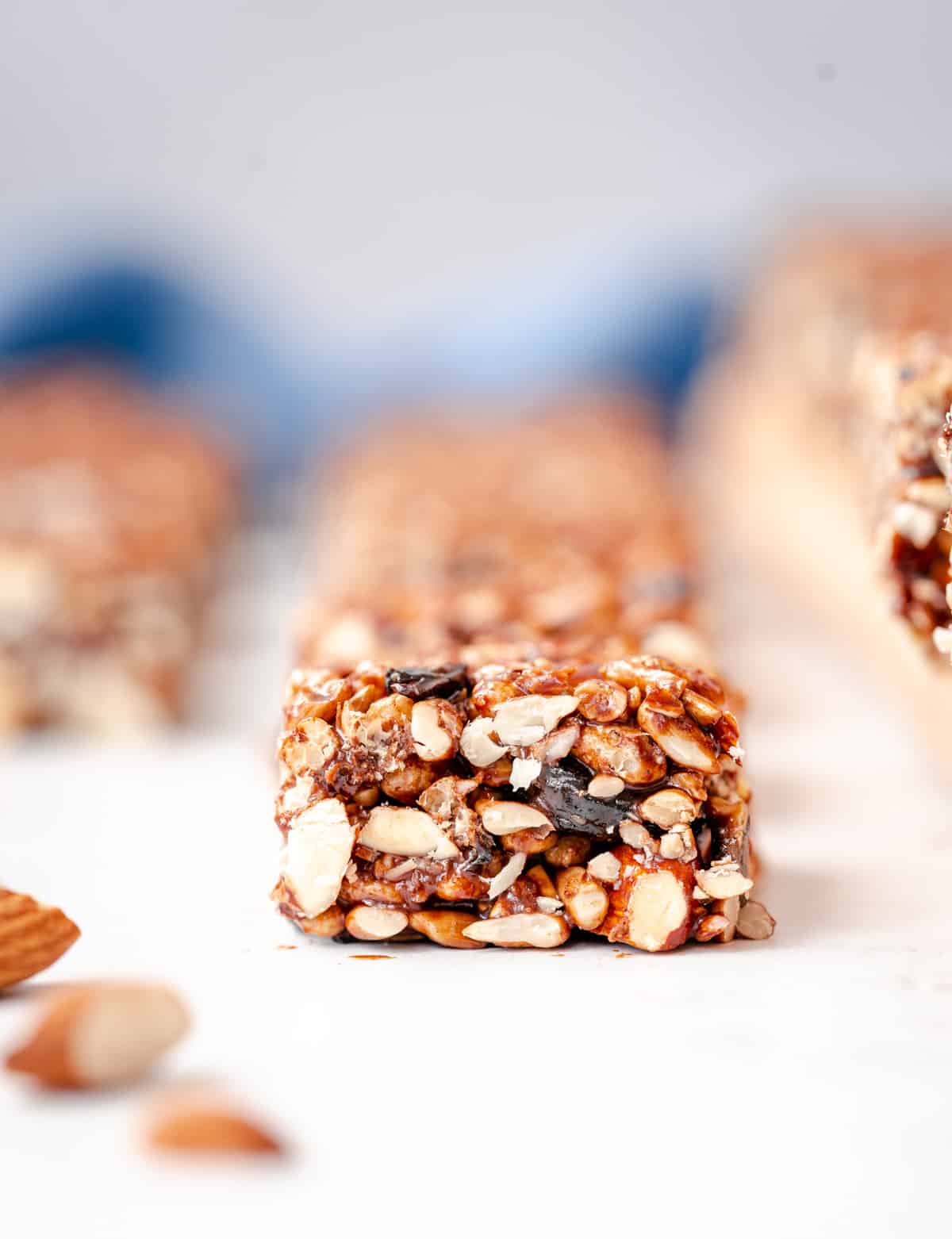 closeup of almond cherry pepita granola bar with scattered almonds
