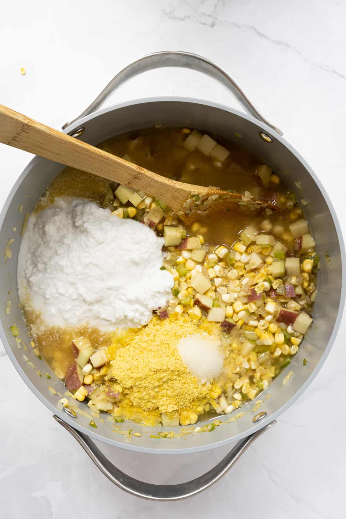 spicy creamy potoato corn chowder process shot in pot.