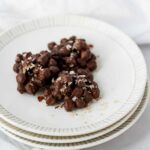 three chocolate chickpea clusters on stacked white plates.