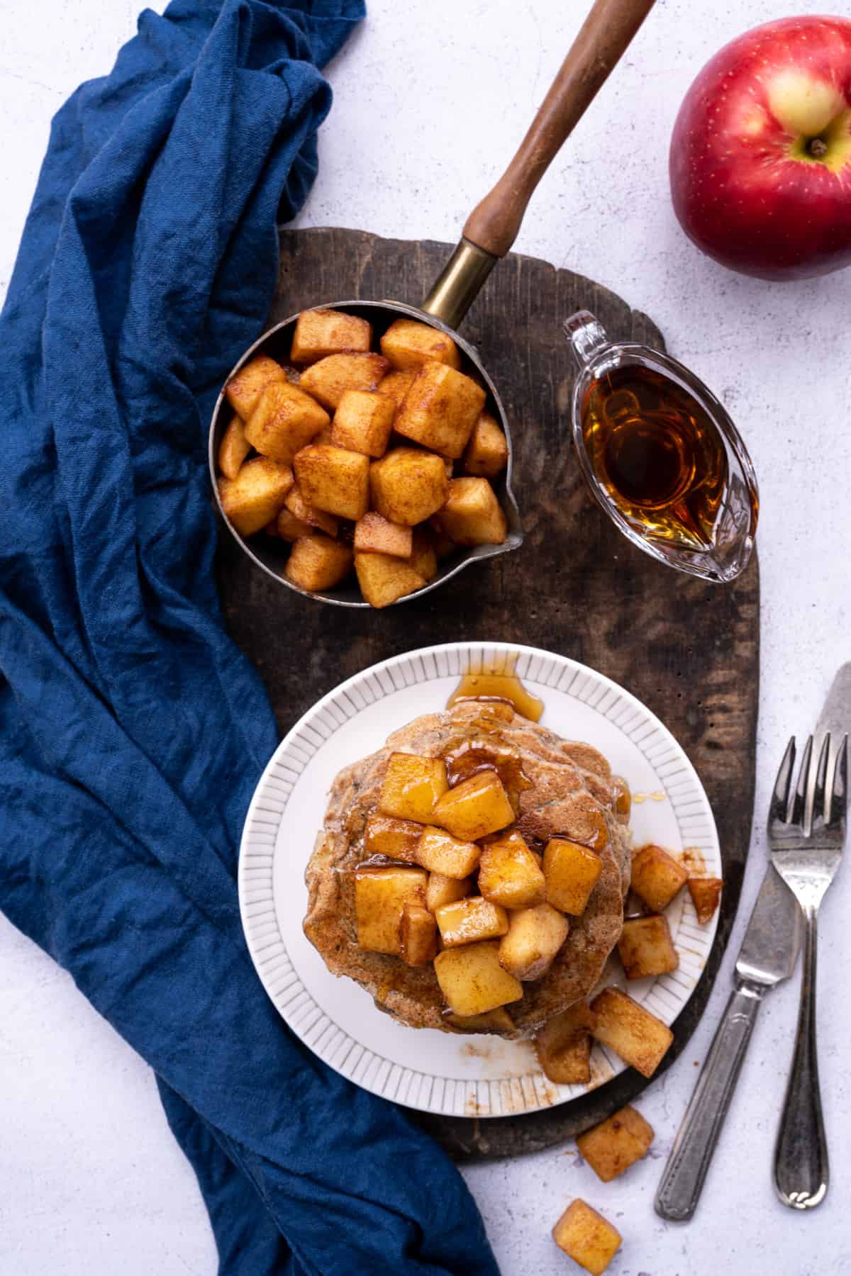 apple buckwheat pancakes on plate with side of maple apples.