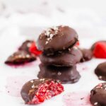 Chocolate covered raspberry bites staked three high with one on the side cut in half to reveal filling.