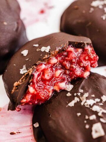 Chocolate covered raspberry chia bite close up cut in half to reveal filling.