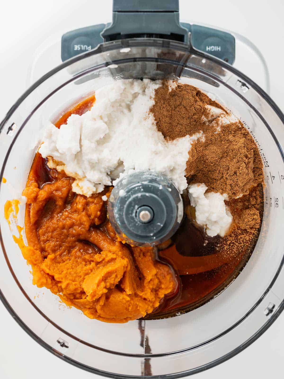 process shot of ingredients for pumpkin ice cream base in food processor but not mixed.