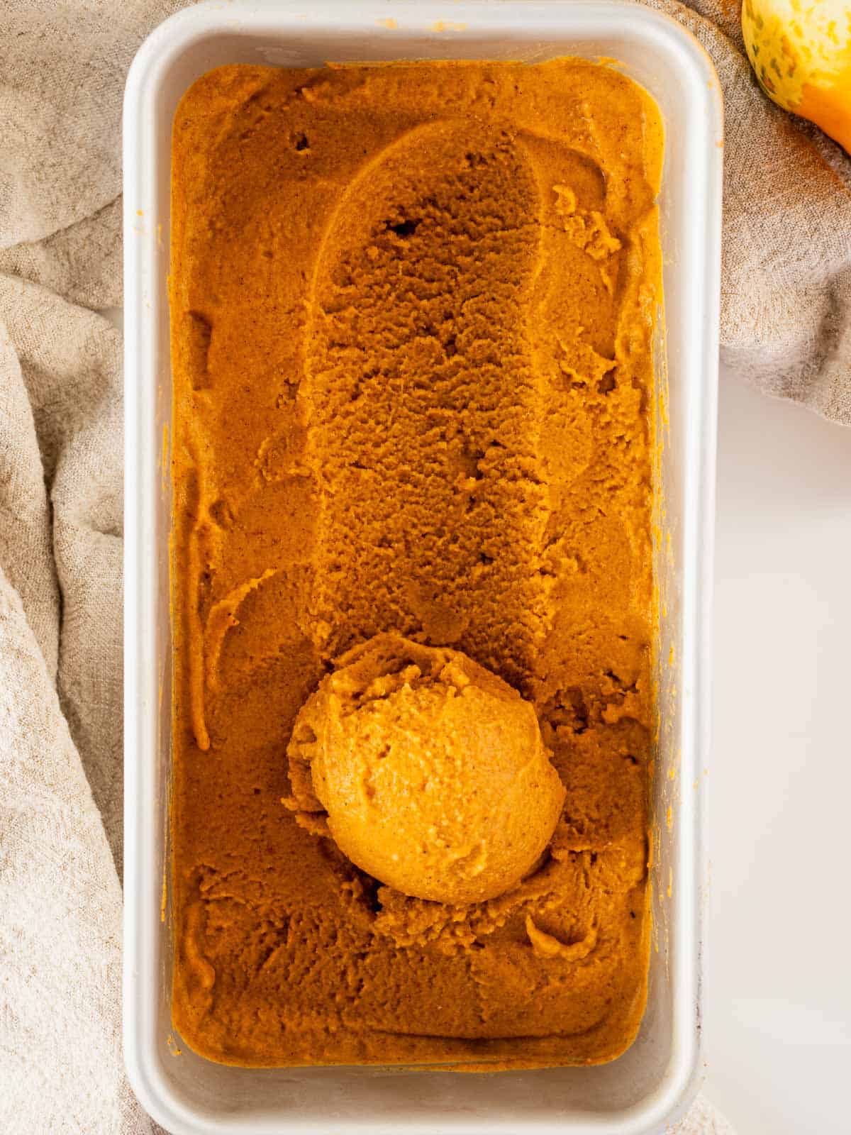 finished and frozen pumpkin pie ice cream in 8x4-inch loaf pan with one ball ice cream rolled in pan.