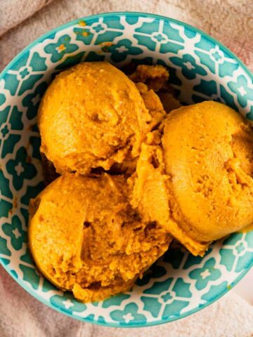 three balls of pumpkin pie ice cream in blue bowl.