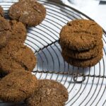 baked ginger molasses cookies piled on round cooling rack, with three cookies stacked.