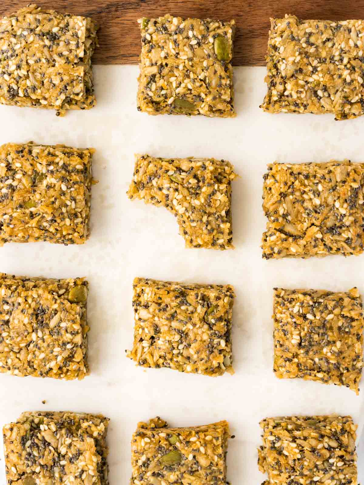 Energy snack and seed bars on a marble board with a bite taken from one bar.