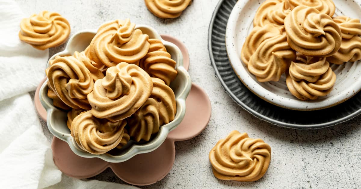 Almond meringue cookies displayed on a bowl and tray.