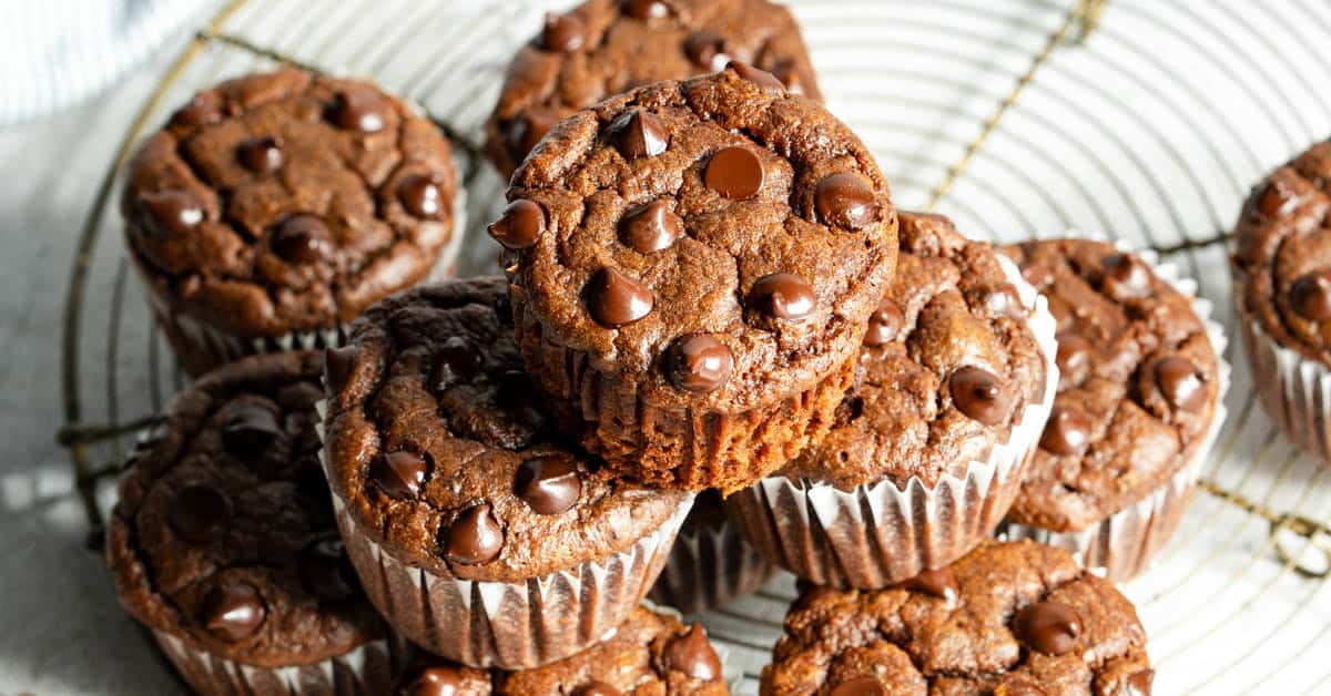 Chocolate sweet potato muffins stacked on round cooling rack.