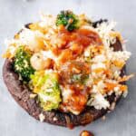 Stuffed portobello mushroom cap filled with broccoli chickpea cauliflower rice and topped with spicy tamari sauce.