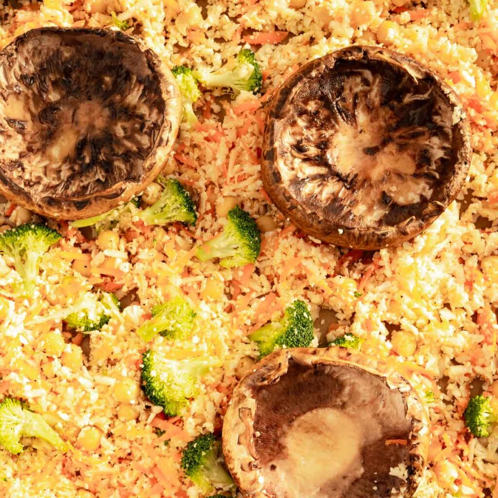 Portobello mushroom caps top side down on a bed of cauliflower rice.