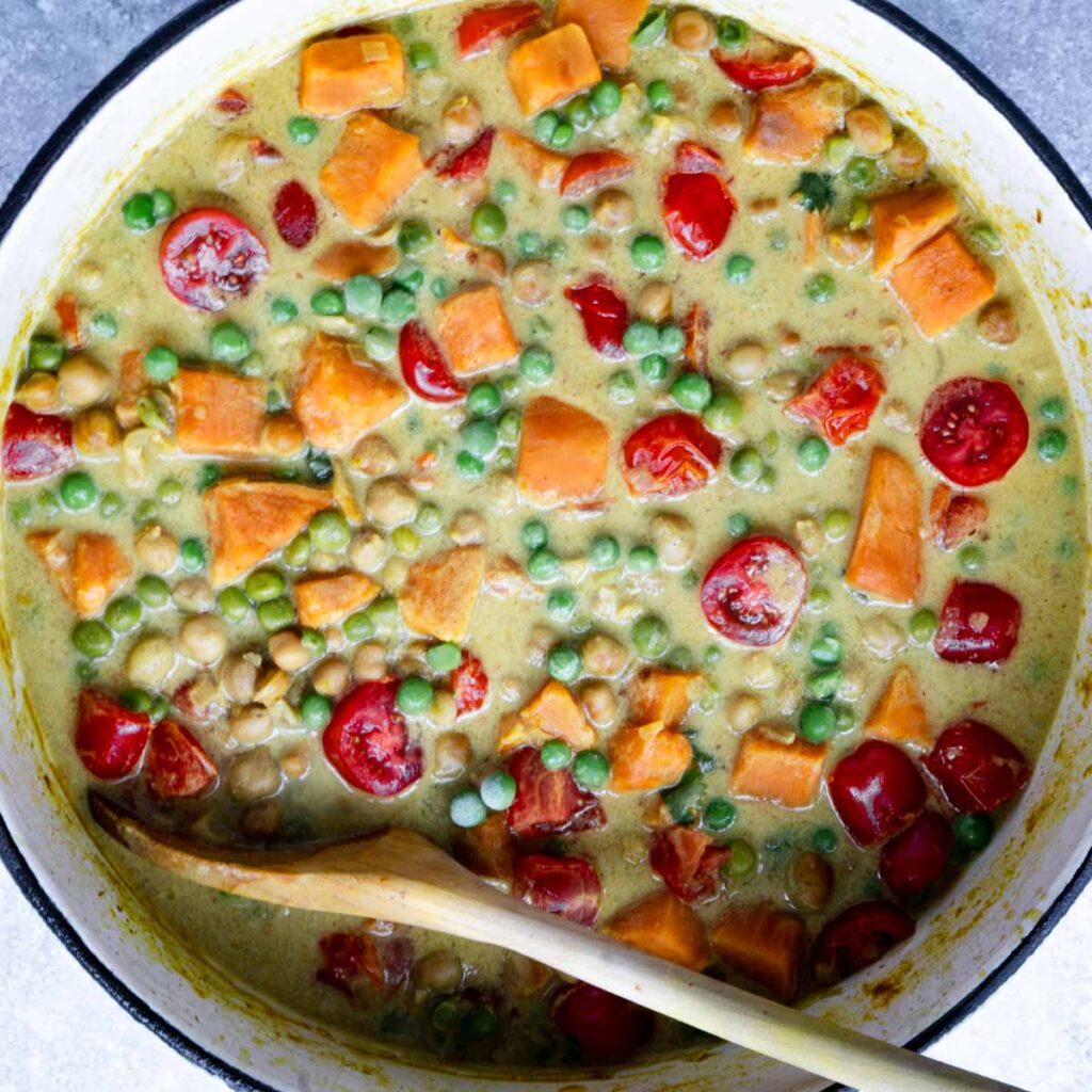 Sweet potato chickpea soup in large pot with wooden spoon.