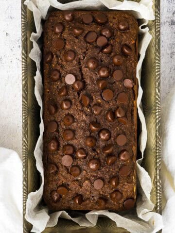 Chocolate bread baked in parchment lined loaf pan with white napkin.