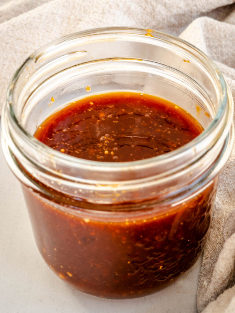 Teriyaki sauce in mason jar with beige napkin.