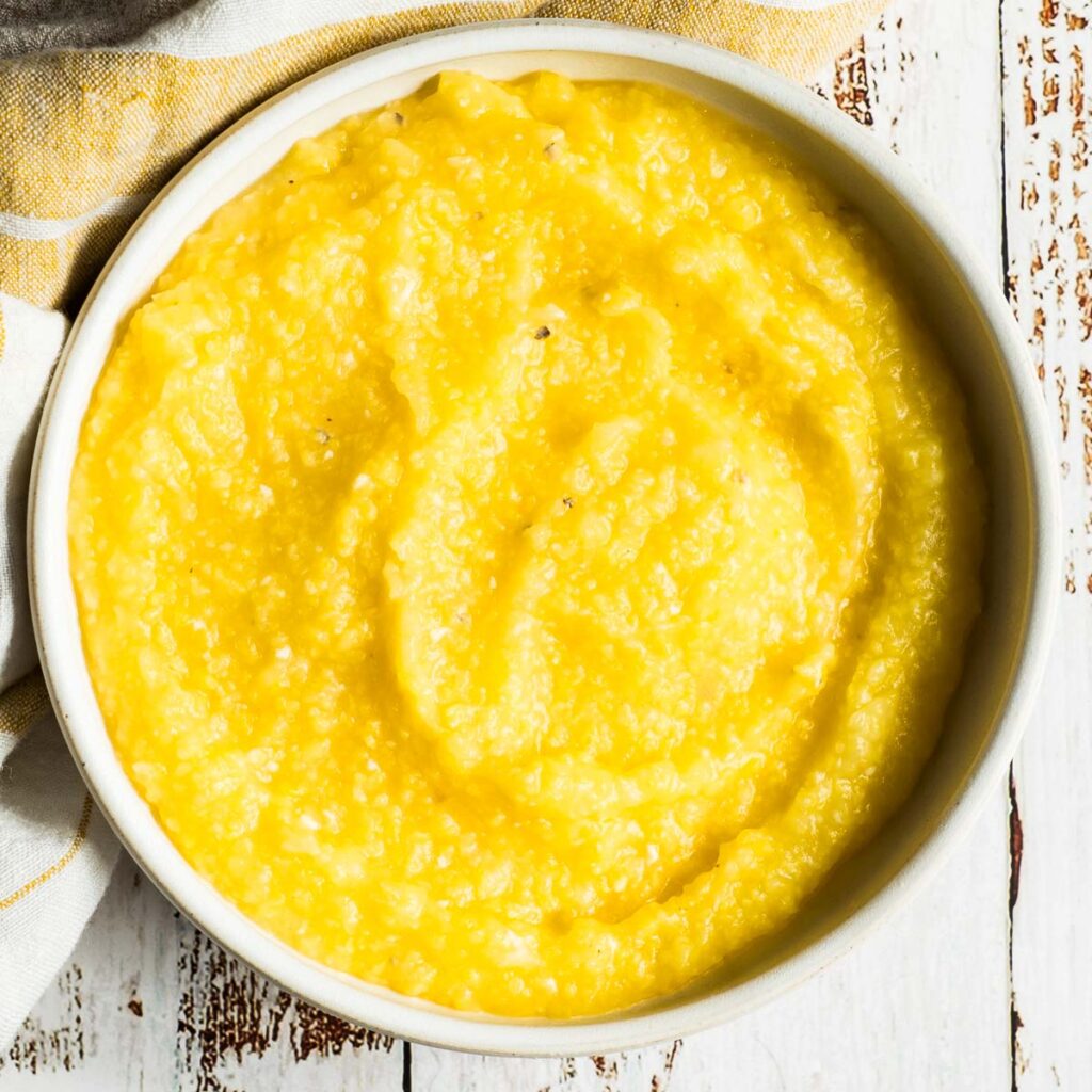 Baked polenta in round white bowl with striped napkin.